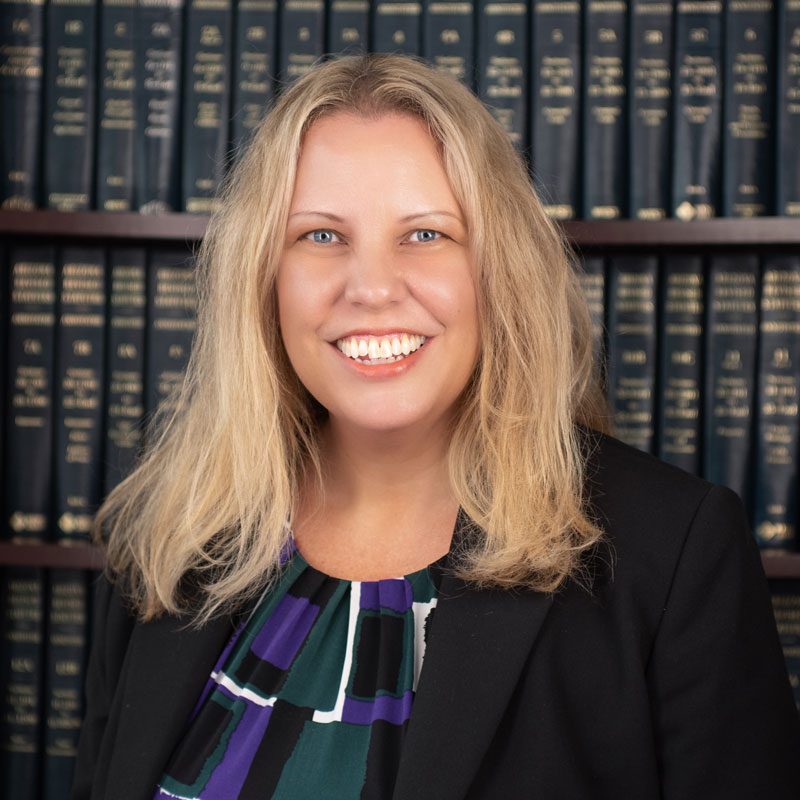 photo of woman in front of bookshelf, black jacket